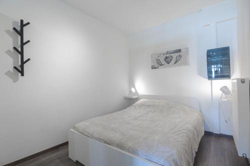 a small white bedroom with a bed in it at Les Figuiers - Appartement Cozy avec Jardin in Andenne