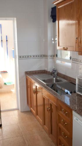 a kitchen with wooden cabinets and a sink at Casa Vromans Alto in Torrevieja