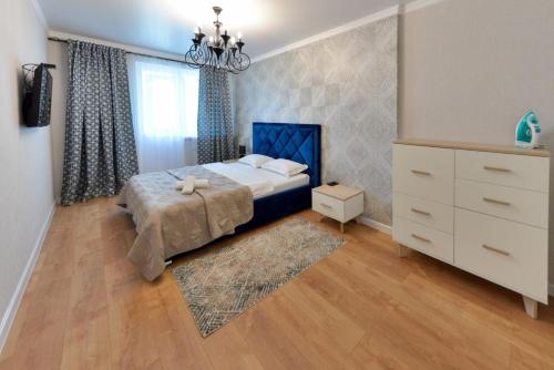 a bedroom with a bed and a dresser and a window at Apartment Lazurniy 7Б in Astana