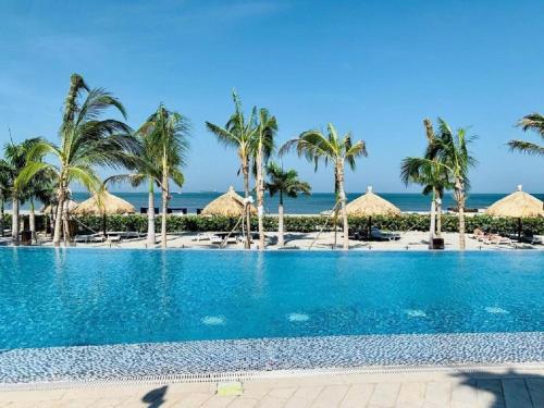 una piscina en la playa con palmeras y sombrillas en Samaria Club de Playa - Pozos Colorados - By INMOBILIARIA VS, en Santa Marta