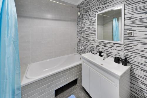 Baño blanco con lavabo, bañera y espejo en Apartment Lazurniy 7Б en Astaná