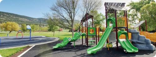 einen Spielplatz in einem Park mit grüner Rutsche in der Unterkunft Road Runner Motel Merritt BC in Merritt