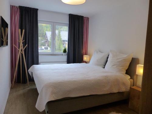 a bedroom with a bed with white sheets and a window at Auerhahn Feldberg in Feldberg