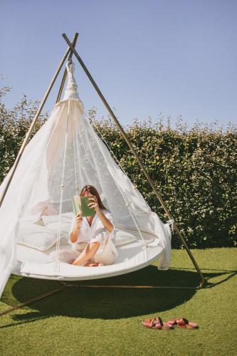 a woman sitting on a swing reading a book at Casa LNNoa Boutique Room whit private pool in Lagos