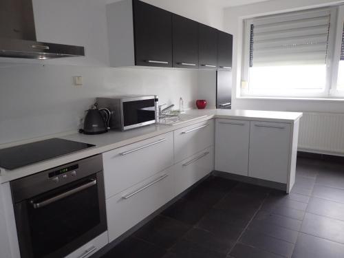 a kitchen with white cabinets and a microwave at Marguerite apartment - parking including in Bratislava