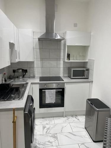 Top Floor Flat - Glasgow West End - Partick في غلاسكو: مطبخ بدولاب بيضاء وفرن علوي موقد