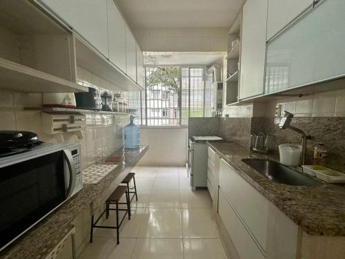 La cuisine est équipée de placards blancs, d'un évier et d'un comptoir. dans l'établissement Amplo & Confortável - Copacabana - Posto 6, à Rio de Janeiro