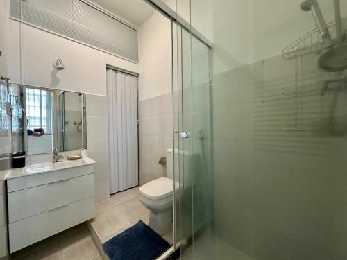 La salle de bains est pourvue de toilettes et d'une douche en verre. dans l'établissement Amplo & Confortável - Copacabana - Posto 6, à Rio de Janeiro