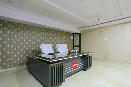 a waiting room with two white chairs and a desk at OYO Flagship Guddan Banquet Hall in Kānpur