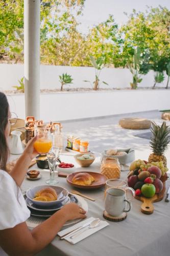 a woman sitting at a table with breakfast food at Casa LNNoa Boutique Room whit private pool in Lagos