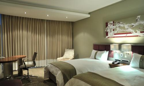 a hotel room with a bed and a desk and a table at Holiday Inn Johannesburg-Rosebank by IHG in Johannesburg