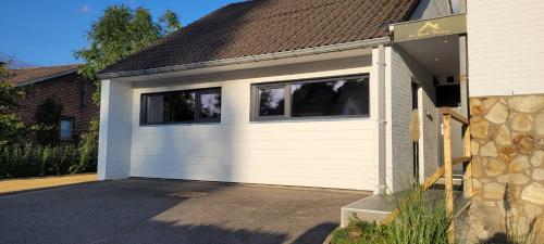 a white garage with two windows on a house at Gîte de Trasenster in Trooz