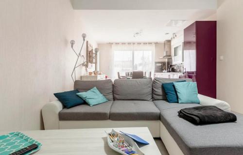a living room with a gray couch and blue pillows at Mag's Dream in Berck-sur-Mer