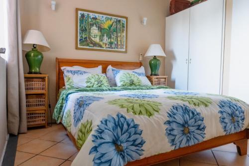 Tamarin Seaside Apartment في تامارين: غرفة نوم مع سرير مع الزهور الزرقاء عليه