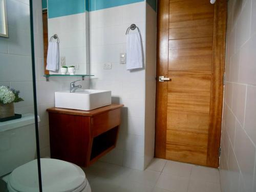 a bathroom with a sink and a wooden door at Lovely condo at Blue Sea Tower near Juan Dolio beach in Juan Pedro