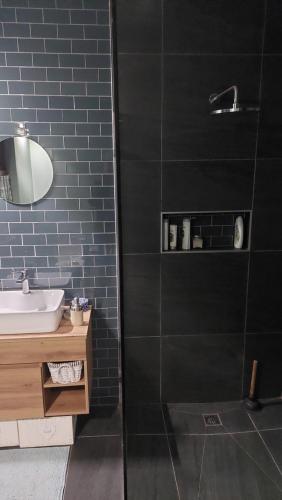 y baño con lavabo y ducha con azulejos negros. en Glenette Residence, en Ciudad del Cabo
