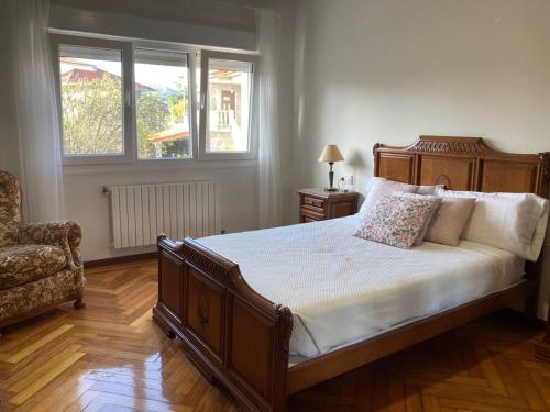 een slaapkamer met een bed en een stoel en 2 ramen bij HyP - Casa Chalo in Sotomayor