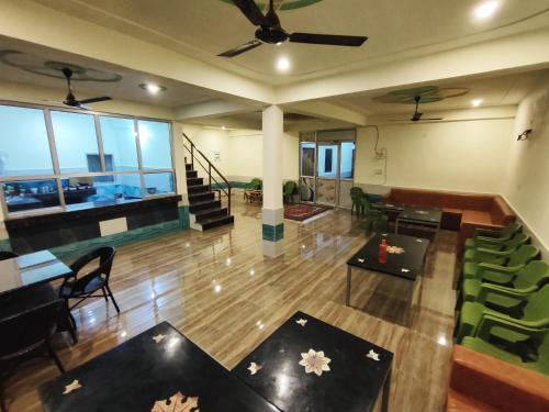 a living room with tables and chairs and a ceiling fan at Sunrise Homestay Agra Near Taj Mahal in Agra