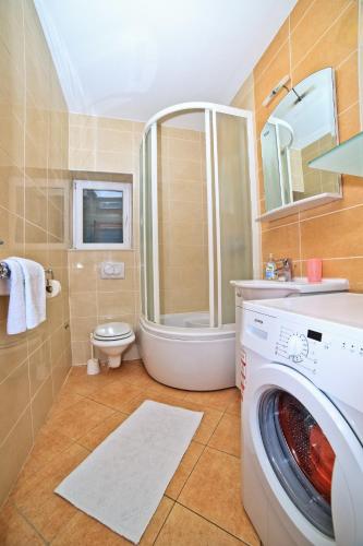 a bathroom with a washing machine and a toilet at Apartments Bozikovic in Podstrana