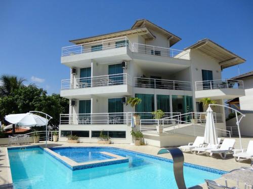 a villa with a swimming pool and a house at Camboinhas Beach Pousada in Niterói