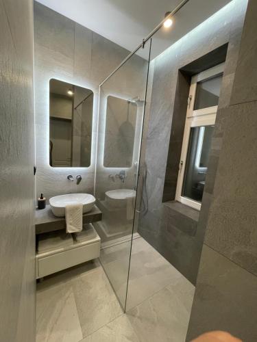 een badkamer met een wastafel en een glazen douche bij Central Apartments Sarajevo in Sarajevo