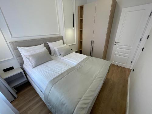 a bedroom with a large bed with white sheets and pillows at Central Apartments Sarajevo in Sarajevo