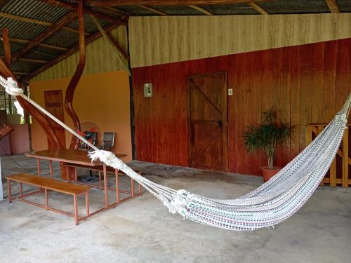 a hammock in a room with a table and a chair at Posada Rural Río Celeste in Rio Celeste