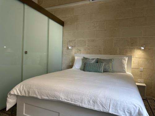 - une chambre dotée d'un grand lit avec des draps et des oreillers blancs dans l'établissement 15 Main Gate, à Il-Birgu
