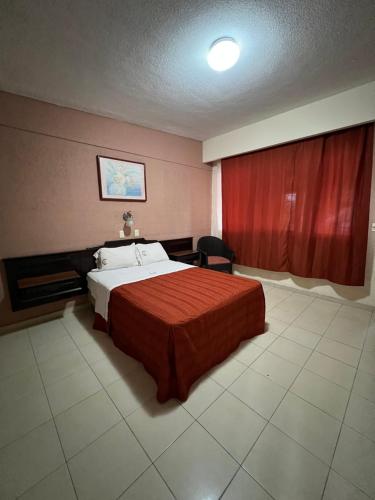 a bedroom with a bed and a red curtain at Hotel La Quinta Posada Real in Culiacán