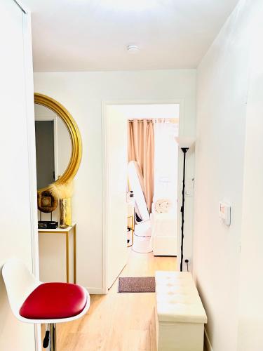 a living room with a red chair and a mirror at LES RÉSIDENCES DE DJIBRIL in Le Blanc-Mesnil