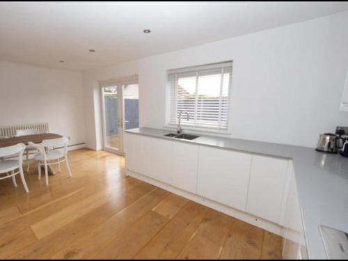 a kitchen with white cabinets and a dining room with a table at Sunny room in a modern house in Cardiff