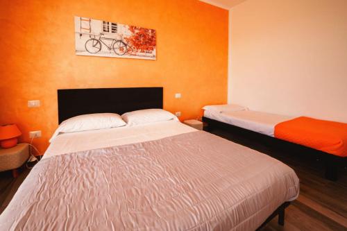 - 2 lits dans une chambre aux murs orange dans l'établissement Casa Charlie, à Arcisate