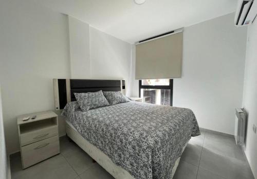 a bedroom with a bed and a nightstand and a window at Paseo Quattro Villa Carlos Paz in Villa Carlos Paz
