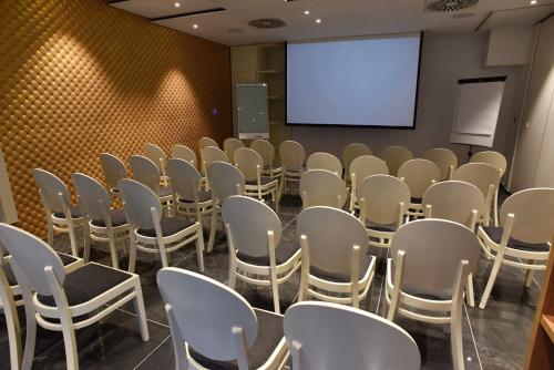 a conference room with white chairs and a screen at Hotel Santiny in Sveta Nedelja