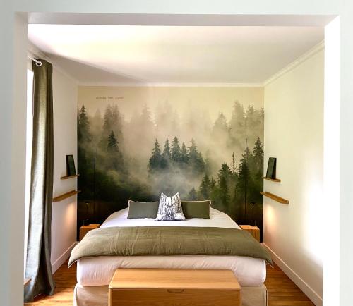 a bedroom with a bed with a painting on the wall at L’orée du bois des rois in Ury