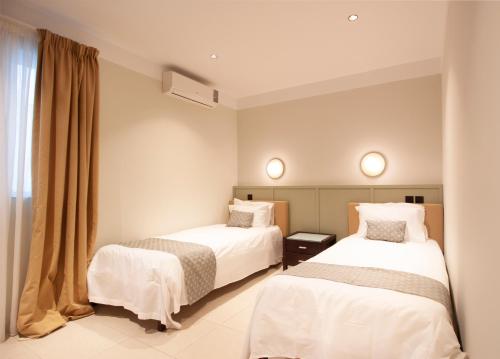 a hotel room with two beds and a window at VILLA JOSEPH in St. Paul's Bay