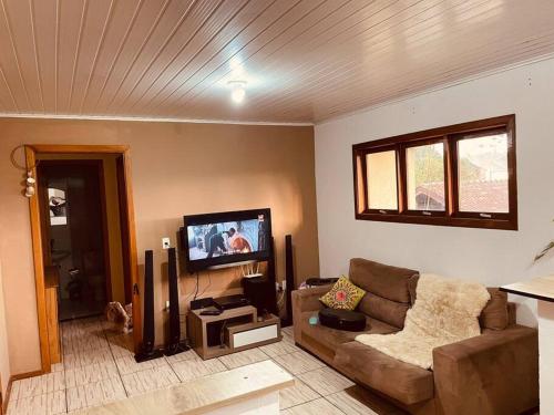 een woonkamer met een bank en een flatscreen-tv bij Apartamento em ótima localização in Canela