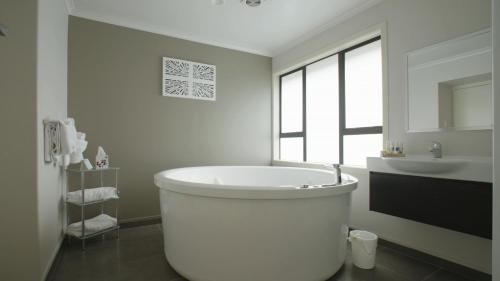 a white bathroom with a tub and a sink at Quality Inn Acapulco Taupo in Taupo