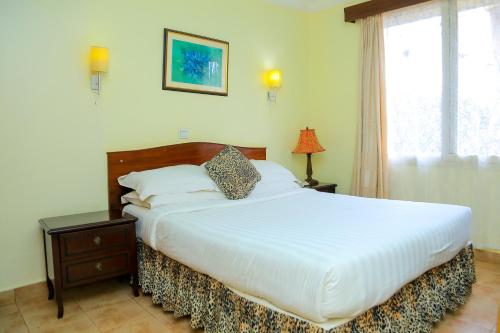 a bedroom with a large white bed and a window at Shangri-la Hotel Muyenga in Bugolobi