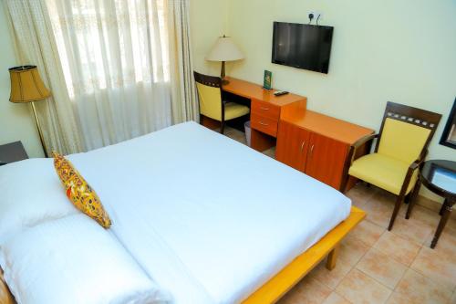a bedroom with a bed and a desk and a television at Shangri-la Hotel Muyenga in Bugolobi
