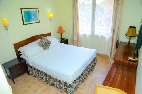 a bedroom with a large white bed and a window at Shangri-la Hotel Muyenga in Bugolobi