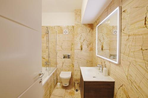 a bathroom with a sink and a toilet and a mirror at Himson-Beige Apartment in Iaşi