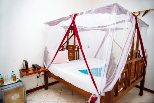a bed with a canopy in a room at La Neisha Hotel Zanzibar in Stone Town
