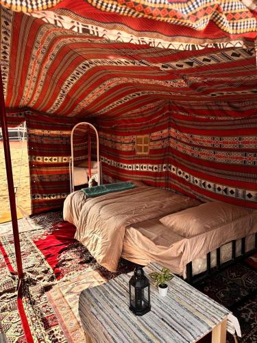 Schlafzimmer mit einem Bett und einem Tisch in der Unterkunft Authentic Desert Camp - Al Wasil 