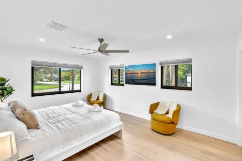 Tropical Oasis with pool 10 mins airport & 5 mins Beach في هوليوود: غرفة بيضاء بسرير وكرسيين