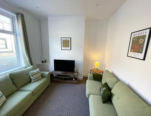 ein Wohnzimmer mit 2 grünen Sofas und einem TV in der Unterkunft 38 Gloucester street by Prestige Properties SA in Roose