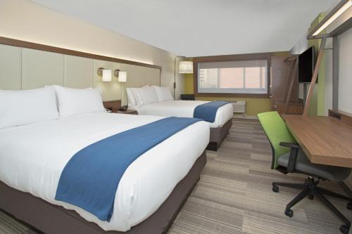 ヒューストンにあるHoliday Inn Express & Suites - Houston IAH - Beltway 8, an IHG Hotelのベッド2台とデスクが備わるホテルルームです。