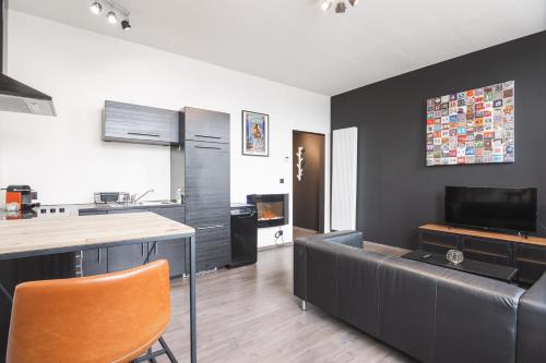 a kitchen and living room with a couch and a table at Les Figuiers - Appart de Standing Tout Equipé in Andenne