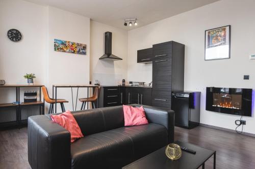 een woonkamer met een leren bank en een keuken bij Les Figuiers - Appart de Standing Tout Equipé in Andenne