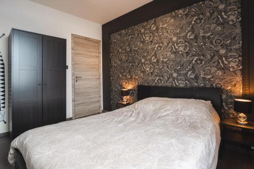 een slaapkamer met een bed en een muur bedekt met behang bij Les Figuiers - Appart de Standing Tout Equipé in Andenne